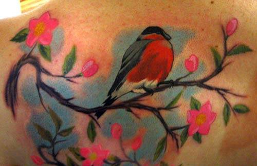 Tatuaggio colorato l&quotuccello sul ramoscello fiorito