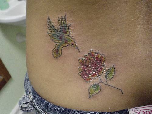 Tatuaggio colorato sulla schiena il colibrì e la rosa