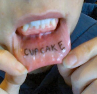 Bottom inner lip tattoo, cupcake, black word