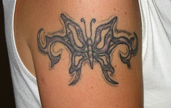 Black tribal butterfly tattoo on arm