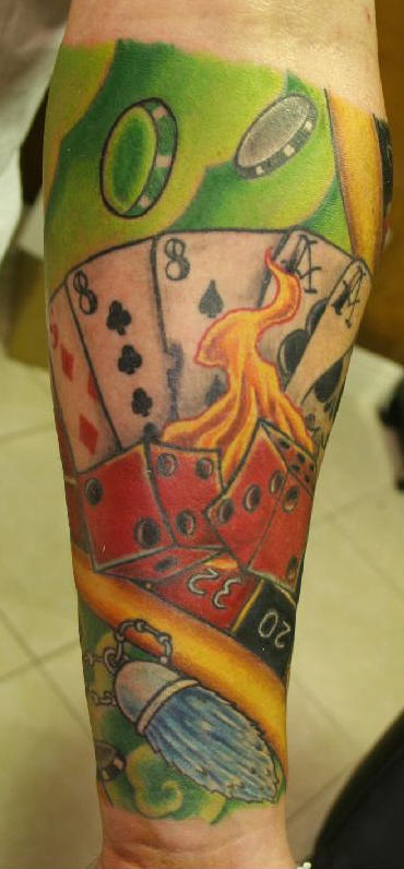 el tatuaje en el brazo de los naipes con dados rojos en el fuego