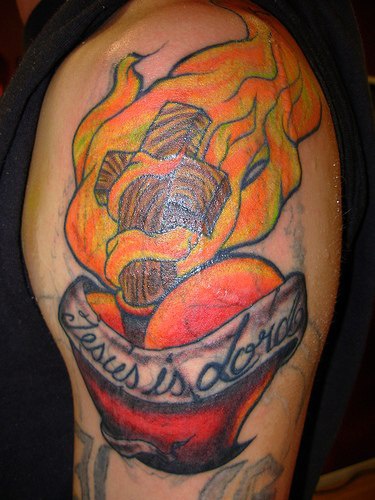 tatuaje colorido de cruz en llamas en el corazón