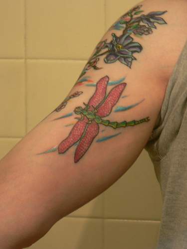 Tatuaje multicolor de libélula en brazo