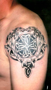 croce celtico con bestie tatuaggio nero sulla spalla
