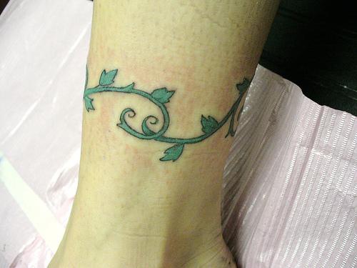 Tree tattoo with green vine around leg