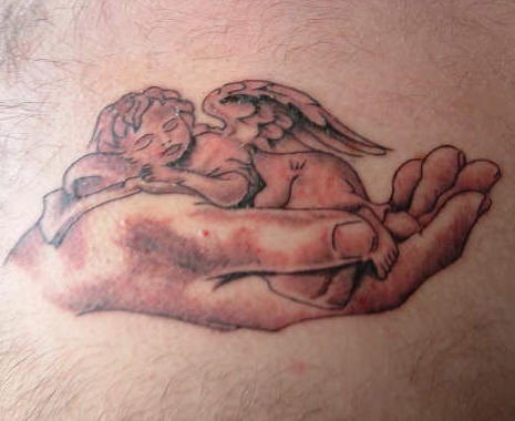 Sleeping cherub in hand tattoo