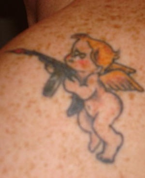 Tatuaje de querubín con un arma Tommy