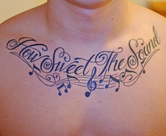 Tattoo von Noten und Aufschrift &quotWie lieblich Klang" auf der Brust