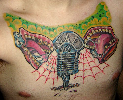 Les mâchoires chantant et un microphone le tatouage sur la poitrine