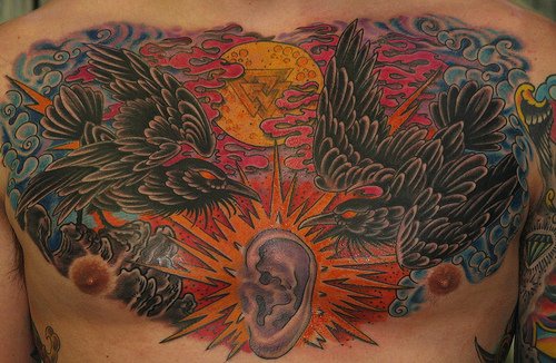 Ear between ravens chest tattoo