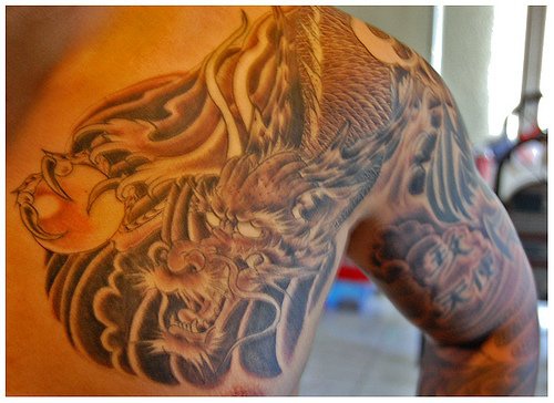Dragone con la sfera tatuato sulla spalla