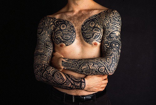 Tattoo von schwarzem Muster auf der Brust und Händen