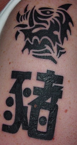 tatuaje de dragón tribál y jerogríficos
