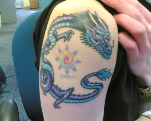 dragone cinese blu e sole tatuaggio sulla spalla