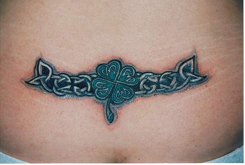 tatuaje en la parte baja de la espalda de tracería céltica con trébol de cuatro hojas