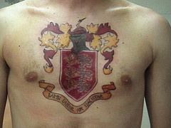 Golden and red heraldic shield tattoo on chest