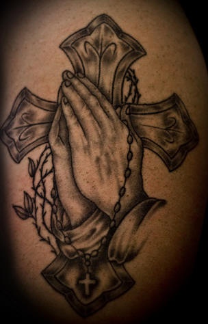 el tatuaje de las manos orantes con la cruz en el fondo