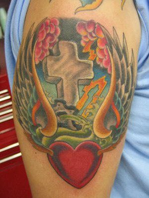 Le tatouage de cœur aillé avec une pierre tombale en forme de croix