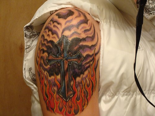 Black cross in flame shoulder tattoo