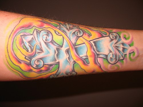 Crystal cross coloured arm tattoo