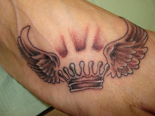 tatuaje en el brazo de corona con alas