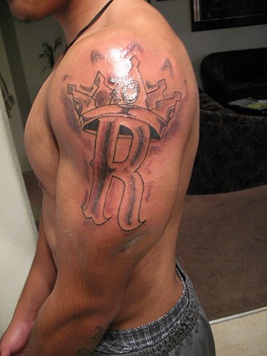 Сrowned monogram tattoo on shoulder