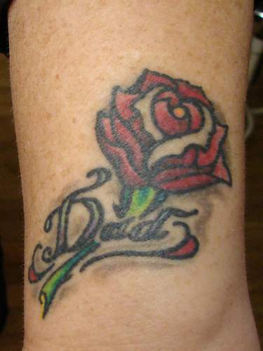 el tatuaje conmemorativo de una rosa con la palabra &quotpapa" hecho a color