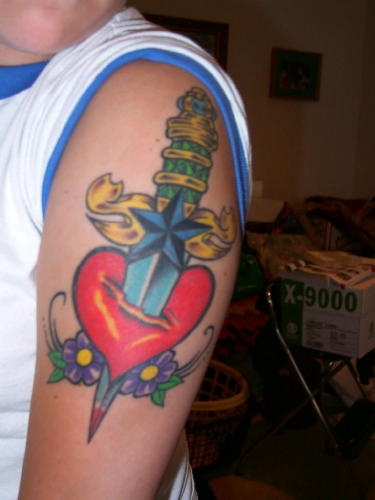 tatuaje colorido de corazón apuñalado con una daga con flores