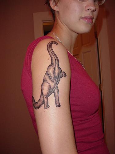 El tatuaje de un apatosaurio en el hombro o brazo en color negro