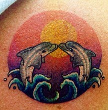 Tattoo with dolphins kiss in sunset