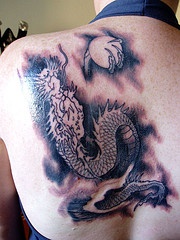 drago con la luna piena in artiglio tatuaggio