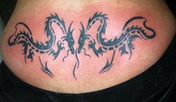 Tatuaje negro de dos dragones en bajo espalda