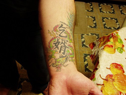 Mostro spaventoso colorato e geroglifici tatuati sul braccio