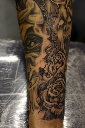 Evil eye and roses sleeve tattoo