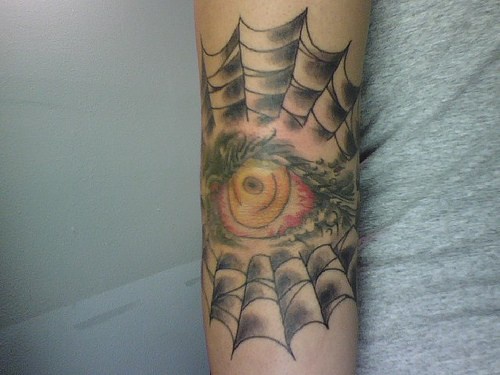 Auge im Spinnfaden Tattoo am Arm