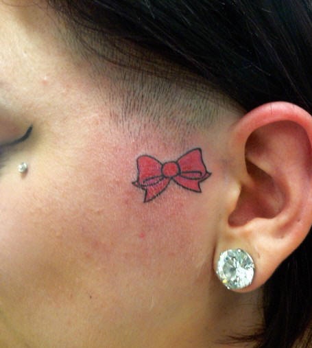 Piccolo fiocco rosso tatuato sulla faccia
