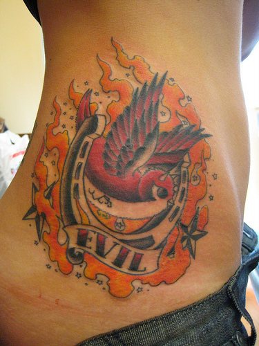 Le tatouage de flanc avec un moineau rouge méchante en flammes