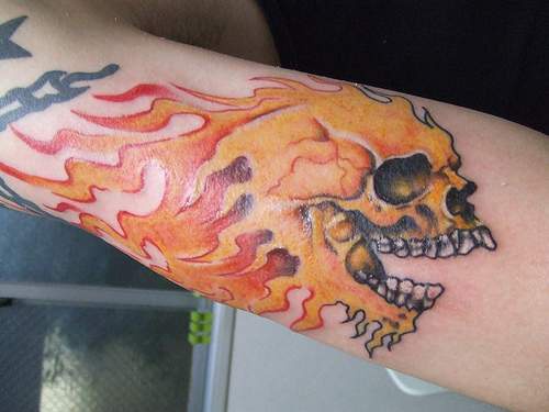 Skull in flame  arm tattoo