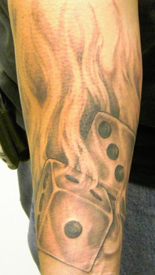 Le tatouage de dés en flammes à l'encre noir