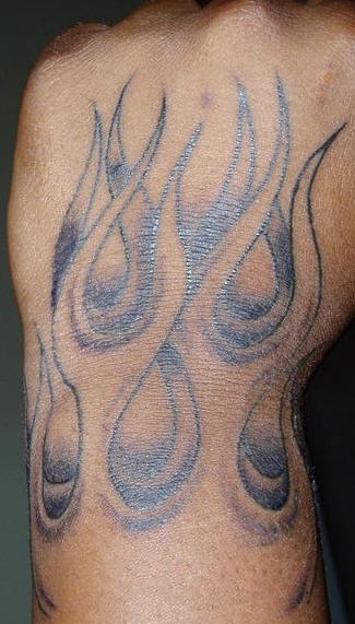 Tatuaje en la mano, llamas de fuego descoloridos