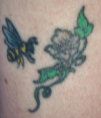 Tatuaje a color de una flor con abeja