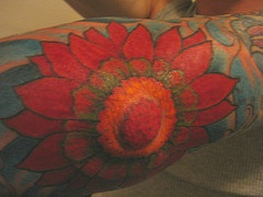 Tatuaje en mano y codo de una flor roja