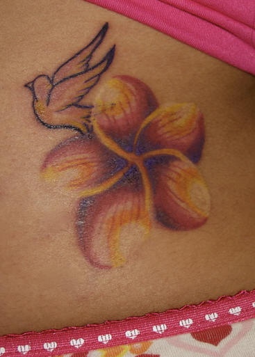 Tatuaje en la cadera, ave doscolorida, flor de colores rojo y amarillo