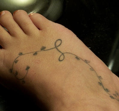 Tatuaje en el pie, hilo con hojas apenas visibles