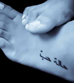 Tattoo von schwarzem Aufschrift auf einer Fremdprache auf dem Fuß