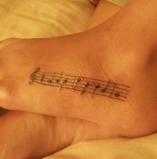 Tatuaggio sul piede melodia scritta sulla carta da musica