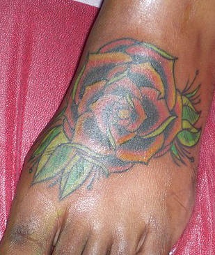 La rosa grande colorata tatuata sul piede