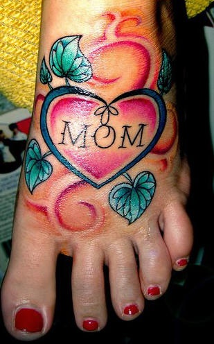 Tatuaje en el pie, hermoso diseño de un corazón entre hojas con inscripción mom