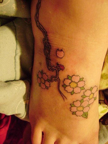 Tatuaje en el pie, tiernas flores en la rama