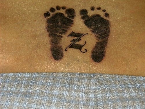 Huellas de pies, tatuaje con símbolo, tinta negra